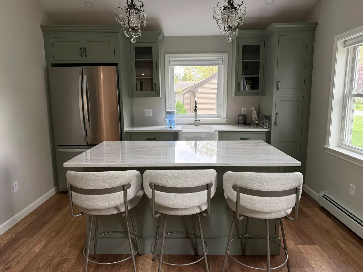 ADU kitchen with sage green cabinets, a white stone island, and three counter stools built by JB Cote Construction
