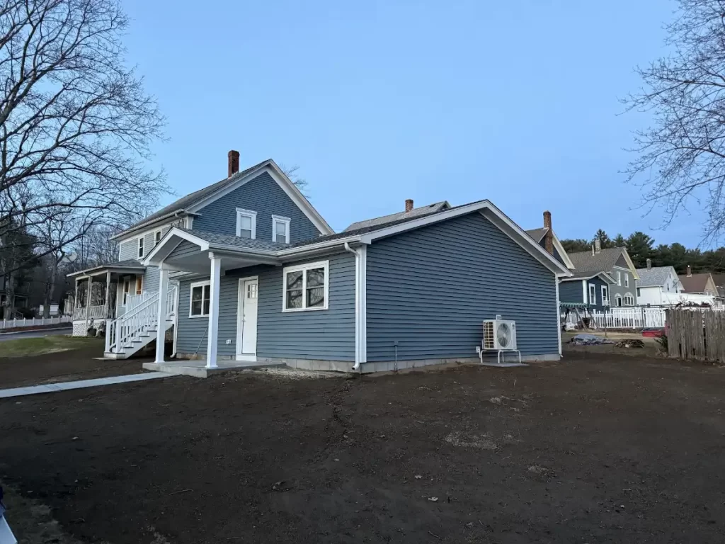 Blue ADU with its own entry and ductless heat pump next to the main house on a Rhode Island lot, built by JB Cote Construction